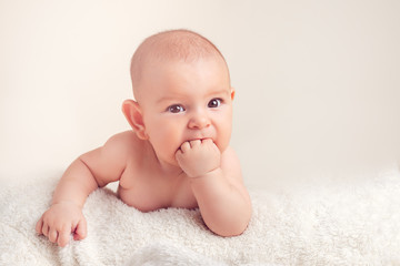 Small cute funny baby infant teething with face expression hands and fingers in mouth sore gums