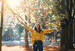 canvas print picture - Casual joyful woman having fun throwing leaves in autumn at city park.