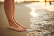 Leinwandbild Motiv Female legs on the beach sand of the sea in summer on vacation.