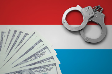 Wall Mural - Luxembourg flag  with handcuffs and a bundle of dollars. The concept of illegal banking operations in US currency