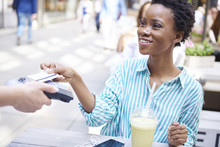 Portrait of smiling woman paying by credit card at pavement cafe
