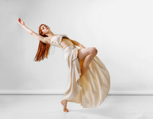Dancer Posing In Studio. Young And Beautiful Redhead Girl In A Beige Long Skirt And Top Dances And Poses In Studio. Copy Space