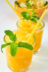 Cold summer melon smoothie with fresh mint leaves on the white background. Melon juice in two glasses. Detox cocktail or healthy diet drink. Close up view