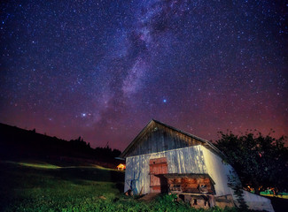 Wall Mural - view at the starry sky and old house on mountain slope.