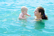 © domaskina - Mother  bathing her baby in azure  sea water