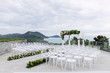Wedding venue setting on the hill, white chairs with flowers decoration, ocean background