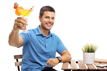 Wall Mural - Young man with a cocktail sitting at a table