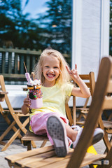 Wall Mural - selective focus of excited child doing rock gesture and holding delicious dessert in cafe