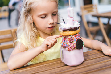 Wall Mural - selective focus of adorable little kid pointing by finger on dessert table in cafe