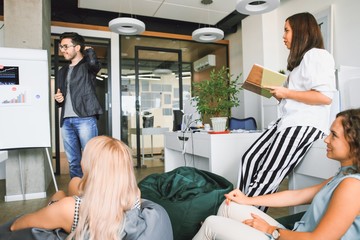 Wall Mural - Young professional team. Group of young modern people in casual clothes having a brainstorm while standing in a modern office