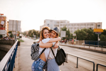 Wall Mural - Two beautiful female friends hugging in the summer in the city.