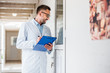 © LIGHTFIELD STUDIOS - handsome veterinarian with clipboard checking rooms at veterinary clinic