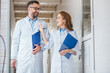 © LIGHTFIELD STUDIOS - smiling vets in white coats walking with clipboards in veterinary clinic and looking at each other