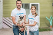© LIGHTFIELD STUDIOS - two volunteers of animals shelter holding pug dog and looking at camera
