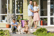 © LIGHTFIELD STUDIOS - happy parents looking at children playing with dog outside house