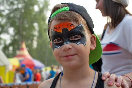 Happy young boy with painted face in superhero