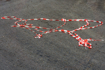 Red white protective tape carried away by the wind is lying under your feet passer-by on the asphalt on the road during a mass holiday