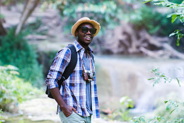 Wall Mural - Traveller african man holding camera with green natural background.