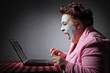 femme ronde drôle en peignoir et bigoudis devant son ordinateur portable