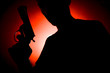 man with a gun silhouette against red spotlight
