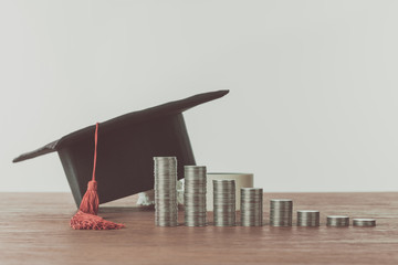 Wall Mural - stacks of coins and graduation cap on wooden table, saving concept