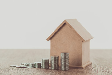 Wall Mural - stacks of coins and small house on wooden table, saving concept