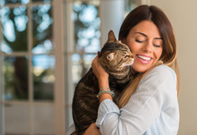 Young Beautiful Woman Smiling And Cuddling Cat With Love At Home.