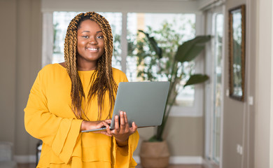 Poster - African american woman with laptop with a happy face standing and smiling with a confident smile showing teeth