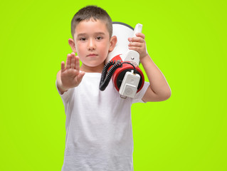 Poster - Dark haired little child holding megaphone with open hand doing stop sign with serious and confident expression, defense gesture