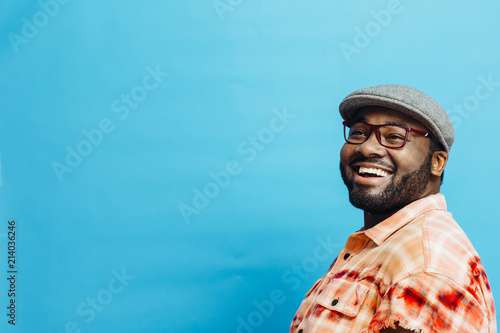 Fotografía Portrait of a happy man in orange shirt looking up, with blue copy space around