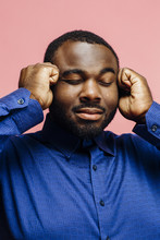 Portrait Of A Plus Size Man In Blue Shirt Holding His Temples With Eyes Closed, Isolated On Pink Background