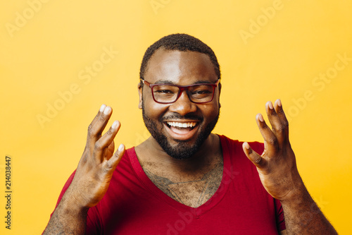 Fotografie, Obraz Portrait of a very happy man with big smile and hands up, isolated on yellow bac