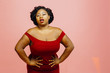 © Carlos David - Confident curvy woman in red dress with hands on waist