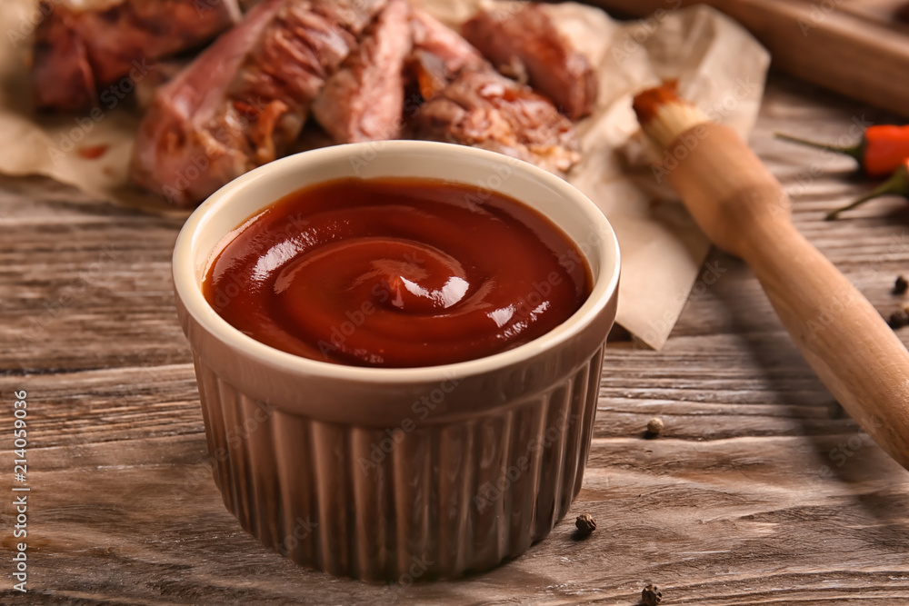 Bowl with barbecue sauce on wooden table