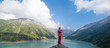 © serikbaib - violinist in a red suit playing the violin on the background of a mountain lake