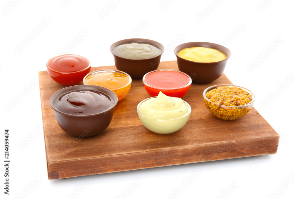 Bowls with different sauces on wooden board, isolated on white