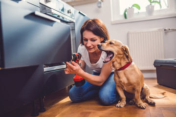 Wall Mural - Woman with dog building kitchen and using a cordless drill