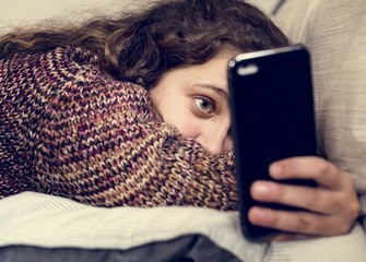 teenage girl using a smartphone on a bed social media and addiction concept