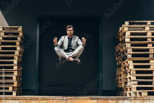 Fotografía handsome young businessman floating in air in lotus pose and meditating in front