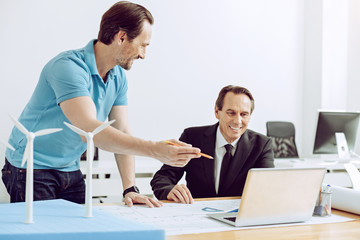 Satisfied client. Happy friendly cheerful client getting his ready project while sitting in front of a laptop in a nice office