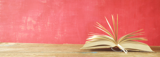 open book on red grungy background, panoramic, good copy space, reading learning, literature concept