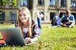 © Viacheslav Yakobchuk - What a lovely day. Cheerful young lady in casual grinning broadly while looking at a screen of her computer and studying outdoors.
