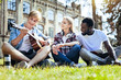 © Viacheslav Yakobchuk - What a wonderful song. Joyful mates in casual grinning broadly while sitting on grass and listening to their friend playing guitar outdoors.