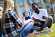 © Viacheslav Yakobchuk - Never bored together. Selective focus on a girl wearing a plain shirt listening to her friends and smiling while all joking during their meeting outdoors.