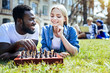 © Viacheslav Yakobchuk - Best teammates. Positive minded young people smiling while chatting and playing a chess game outdoors.