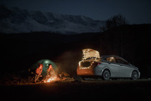 Couple In Camping With Campfire At Night On Mountain Background