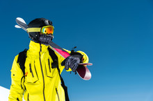 Skier Standing On A Slope. Man In A Light Suit, The Helmet And Mask In Skiing Is To Ski. In The Background Snow-capped Mountains , Skiers . Caucasus Mountains, Elbrus, Russia