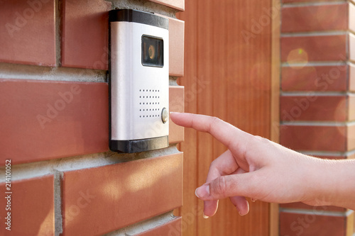 Photographie The female hand presses a button doorbell with intercom