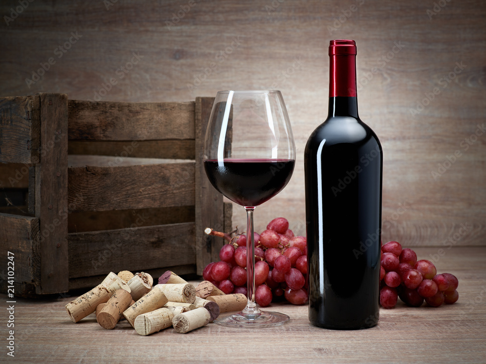 Weinflasche mit Korken, Trauben, Glas Wein, Weinkiste auf Holztisch mit Holzhintergrund Stock Photo