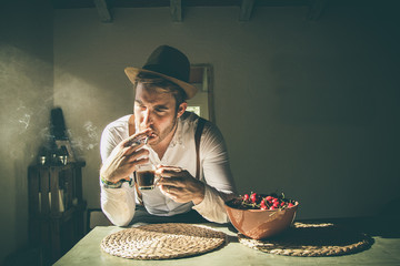 Guy drinking coffee and smoking a cigarette.